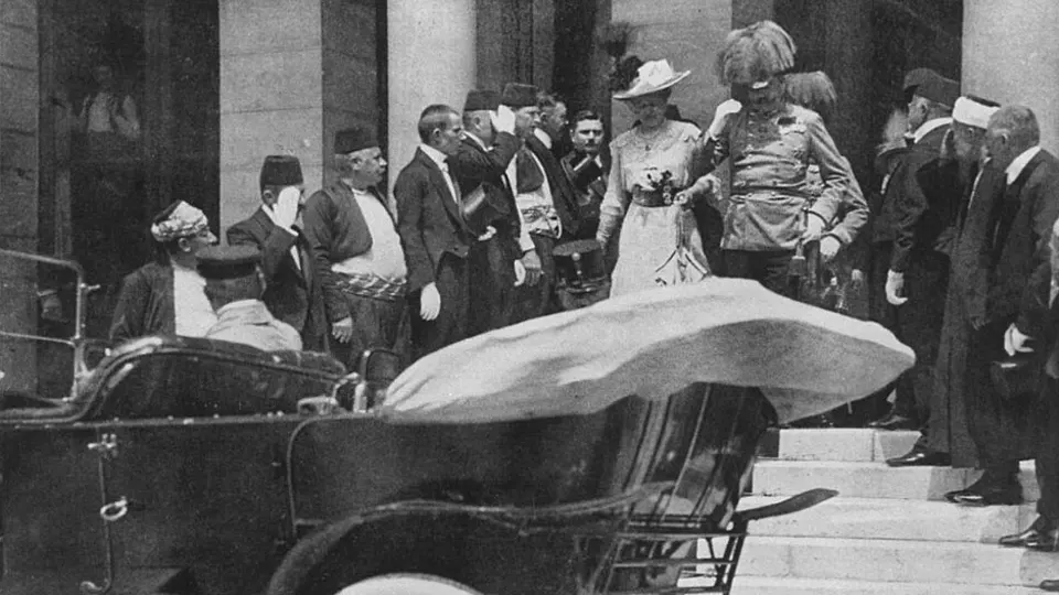 Arcyksiążę Franciszek Ferdynand i jego żona Zofia schodzą po schodach ratusza do odkrytego samochodu, wokół nich urzędnicy i oficerowie.